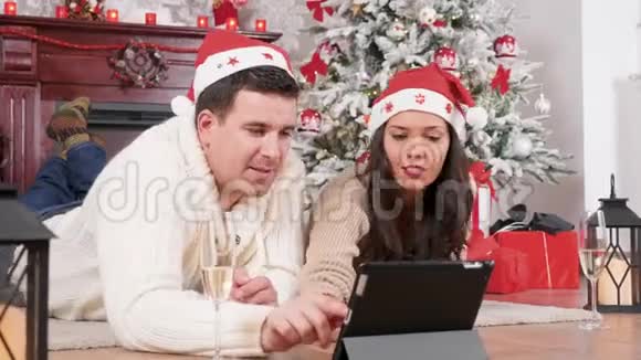在网上订购礼物的圣诞装饰房间里的快乐情侣视频的预览图
