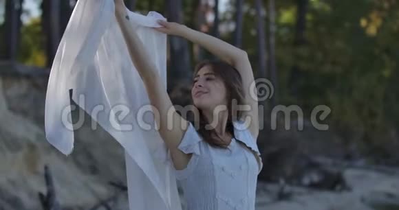 微笑的白种人女人站在森林里戴着被风吹过的浅白色围巾抬头看着漂亮姑娘视频的预览图