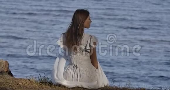 一个优雅的白种人女人坐在海滩上思考美丽的女孩视频的预览图
