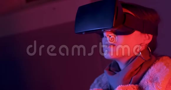 美丽的年轻女子使用虚拟现实眼镜霓虹灯照明背景喜欢触摸虚拟的女孩视频的预览图