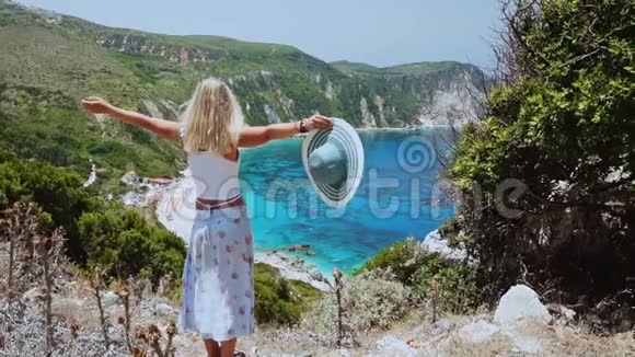 在希腊的凯法洛尼亚岛美丽的金发美女在海滩度假时举手幸福生活视频的预览图