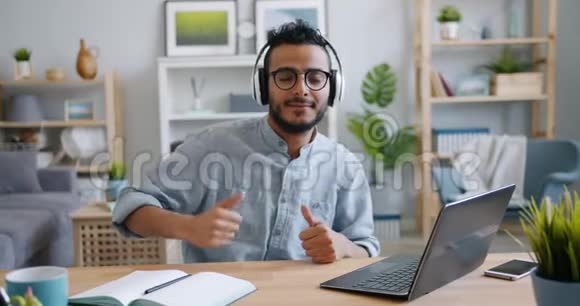 帅气的阿拉伯年轻人带着笔记本电脑在家工作享受音乐视频的预览图