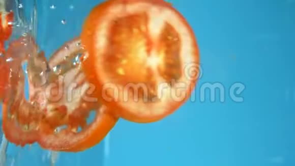 垂直射击切碎的西红柿掉进水里蓝色烹饪背景视频的预览图