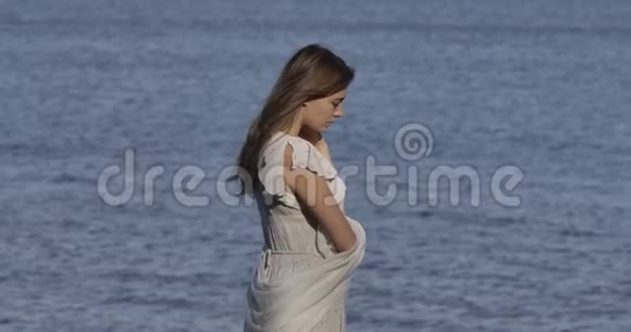 站在海浪背景下的一个穿着浅白色衣服的体贴的高加索女人的侧面景色有魅力的女孩视频的预览图
