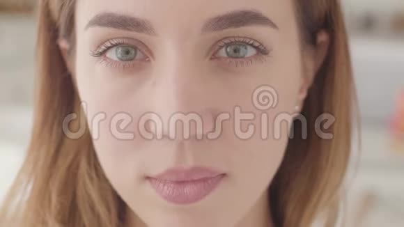 一个美丽的白人女人的极端特写灰色的眼睛看着相机微笑视频的预览图