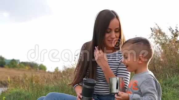 一家人在露营时喝热水瓶里的茶妈妈给儿子一杯热茶视频的预览图