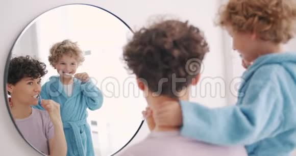 年轻女子和小男孩在浴室里刷牙照镜子视频的预览图