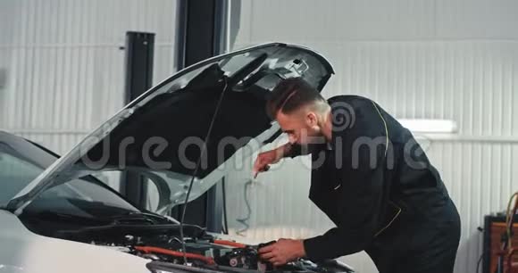 在车库里一个穿着特殊制服的机械师仔细检查汽车的油位然后开始修理视频的预览图