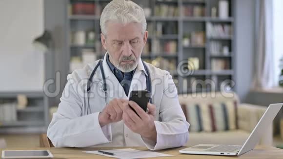 资深老年医生在诊所使用智能电话视频的预览图