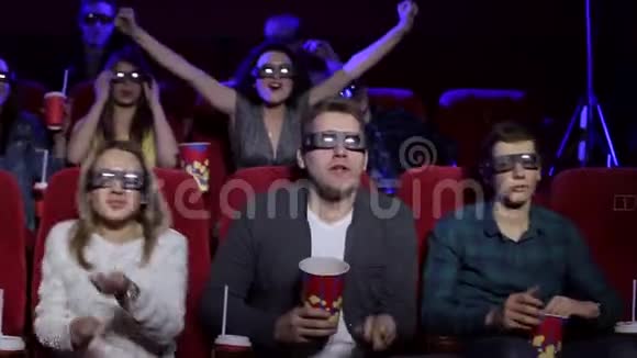 一个朋友在电影院戴着眼镜看3D电影他们高高举起双手视频的预览图