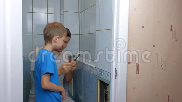 爸爸和儿子在家里一起修理把厕所里的墙上的瓷砖去掉视频的预览图