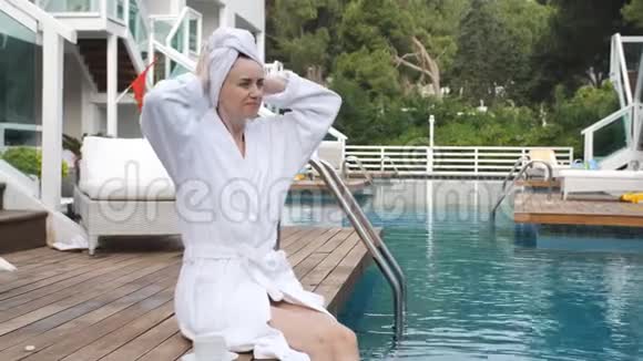 优雅的女人穿着浴袍后洗了个热水澡坐在码头乡村别墅里欣赏日落视频的预览图