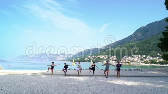 早上一群人在美丽的亚得里亚海海滨做瑜伽姿势视频的预览图
