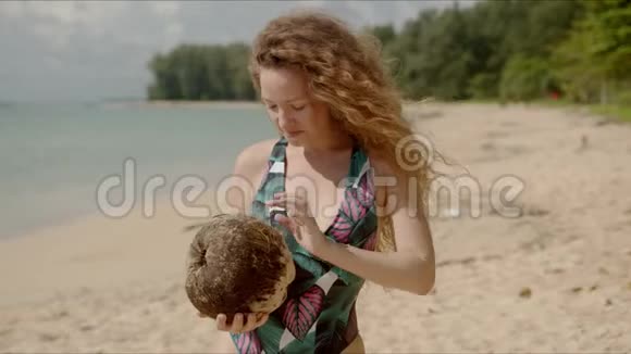 毛茸茸的雌性在海滩上摇动椰子视频的预览图