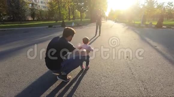 可爱的小女孩和爸爸妈妈一起在公园里散步可爱十个月宝宝走路美丽快乐的女孩视频的预览图