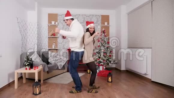 白人夫妇手里拿着香槟酒杯跳舞圣诞节装饰的房间视频的预览图