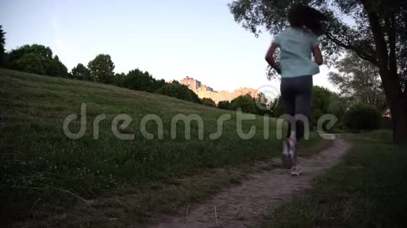 穿着t恤和紧身裤的女孩沿着绿色公园小径奔跑视频的预览图