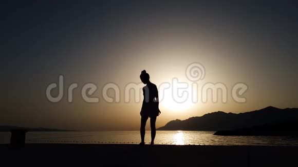 日落时分在海滩上自由活动的女性瑜伽剪影视频的预览图