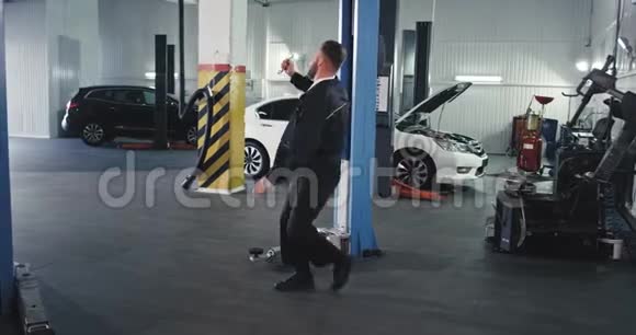 在一辆宽敞的汽车里一个穿制服的机械师在休息时兴奋地跳舞他把车固定在车库里视频的预览图