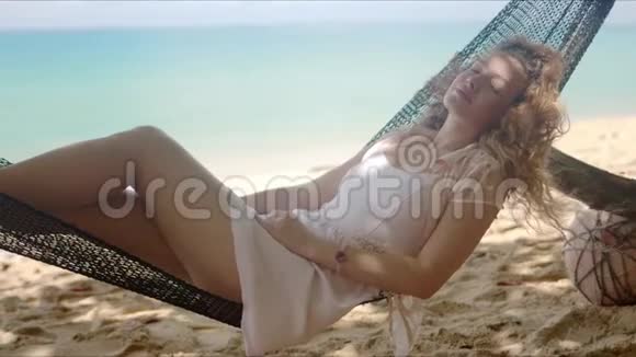 迷人的女人幻想着在海滩上的吊床上闲逛视频的预览图