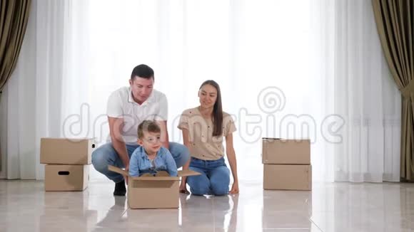 父亲骑着快乐的小儿子在大空纸板箱里视频的预览图