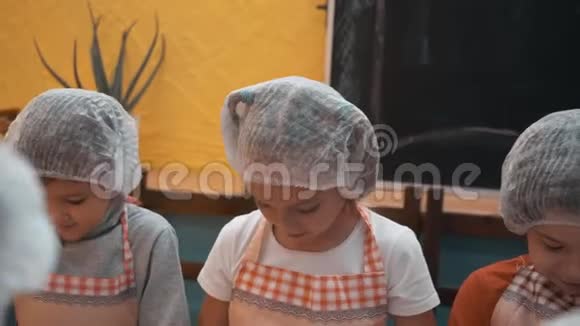 在烹饪学校的烹饪课上孩子们戴着一次性帽子和围裙做面团快乐的孩子们准备面团视频的预览图