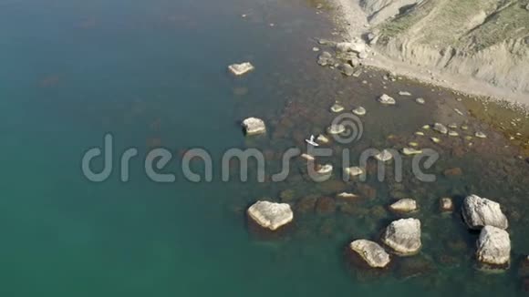 超级冲浪者在从水中升起的岩石之间游泳狭长的岩石海岸带视频的预览图