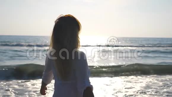穿比基尼和衬衫的年轻女人在海边散步和旋转美丽的女孩抚摸着她的金发视频的预览图
