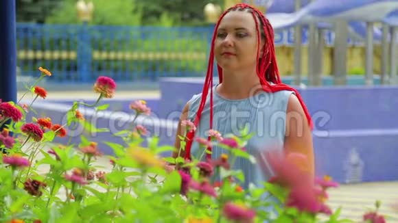 红头发的女人欣赏公园里美丽的花朵视频的预览图