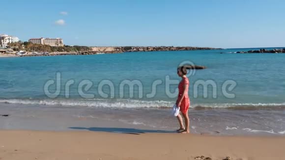 年轻迷人的孤独女孩走在海边的沙滩上漂亮的白种人女人穿着红色的衣服在海边散步裸舞视频的预览图