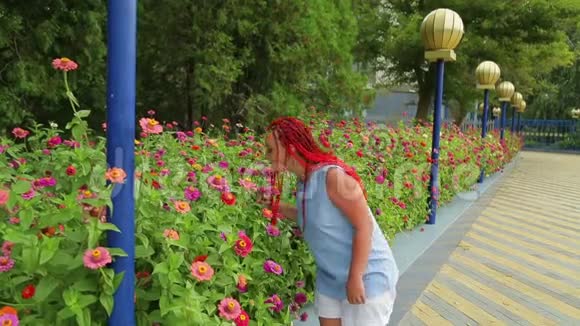 红发女子欣赏公园里美丽的花朵视频的预览图