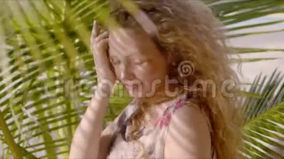 微笑的女士站在棕榈树的树荫下视频的预览图