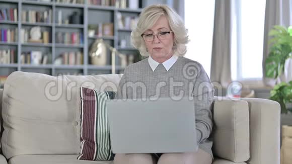 精疲力竭的老妇人在笔记本电脑上工作背部疼痛视频的预览图