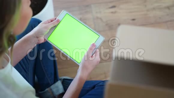 女人看着绿色屏幕的平板电脑女人用垫子双手合拍视频的预览图
