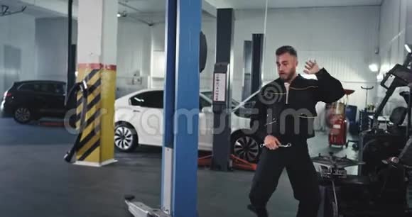 在摄像机前的机械师一位现代服务的汽车人检查汽车在工作中跳舞他很享受视频的预览图