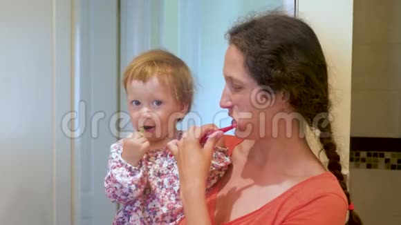 妈妈教孩子刷牙母女俩一起在卫生间刷牙母亲和孩子的家庭视频的预览图