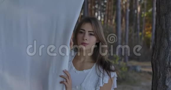 一个年轻漂亮的高加索女人的肖像棕色的眼睛站在森林里环顾四周漂亮姑娘视频的预览图