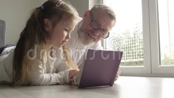 带着戴眼镜的老人一起在地板上看书的少女微笑视频的预览图