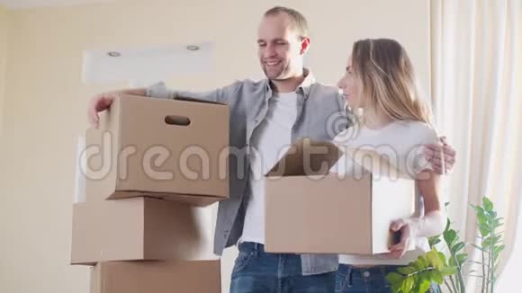 一对幸福的年轻夫妇带着纸板箱在他们的新房子里视频的预览图