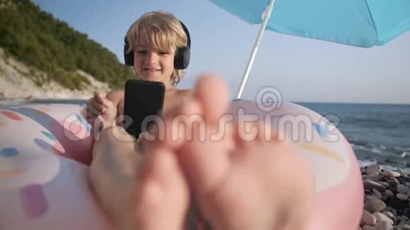 可爱的孩子在智能手机上听音乐在海滩上唱歌视频的预览图