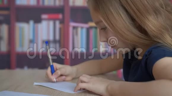 书桌上写着纸的可爱专注女孩的特写镜头视频的预览图