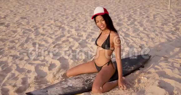 穿比基尼的性感女人坐在沙滩冲浪板上视频的预览图