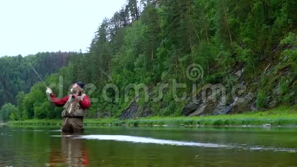 去钓鱼一条山河一位留着长发和圣诞老人胡须的老人站在水里手里拿着一根鱼竿视频的预览图