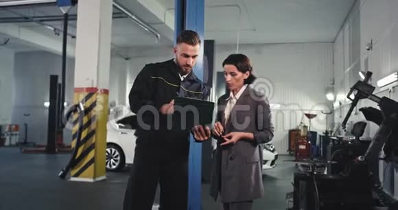 成熟的机械师和迷人的女士在去汽车检查问题之前在一些文件上签字视频的预览图