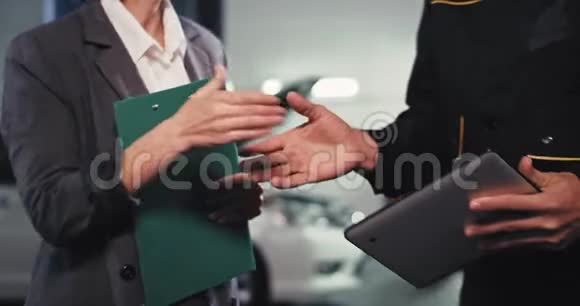 漂亮的女士穿着西装在镜头前和一个汽车修理工握手他们做了交易然后进去了视频的预览图