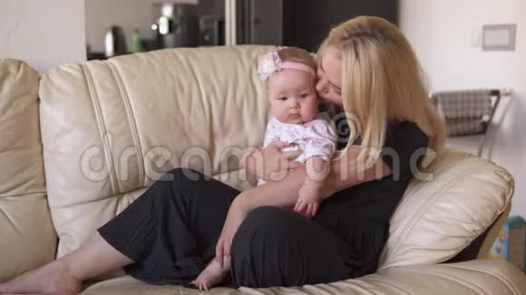 妈妈在沙发上拥抱她可爱的宝宝视频的预览图