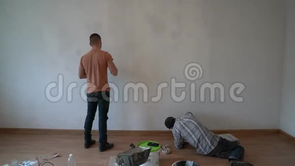 两个画家一起工作用油漆刷涂墙壁白色内部视频的预览图