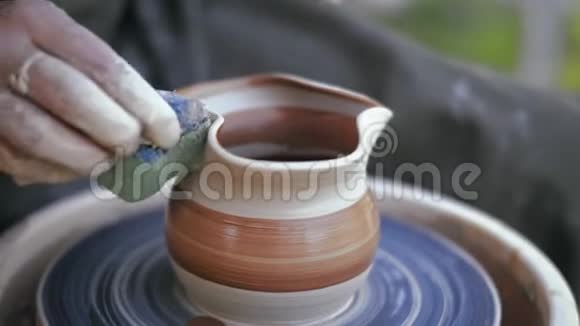 特写陶工在陶工的圆圈上擦拭准备好的锅视频的预览图