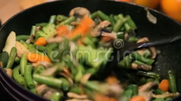 用蘑菇西兰花胡萝卜在锅里炖煮带铲的视频的预览图