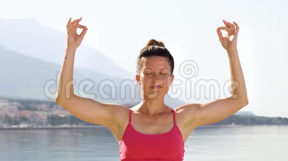 地中海海边练习瑜伽的成年女子闭上眼睛的弧形镜头视频的预览图